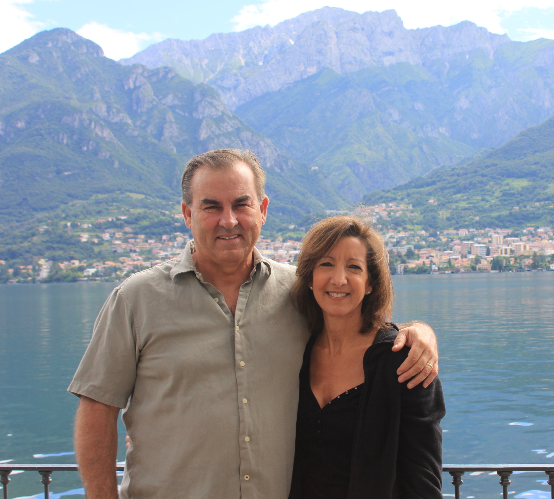 Hosts standing by Lake Como with mountains in the background